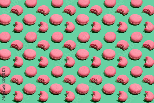 Colorful macaroni seamless pattern. Pink cookies over mint background