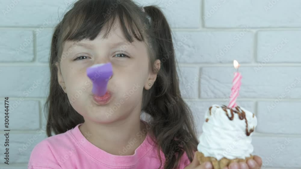 Celebrate with party blowers. Happy little girl with cake with burning