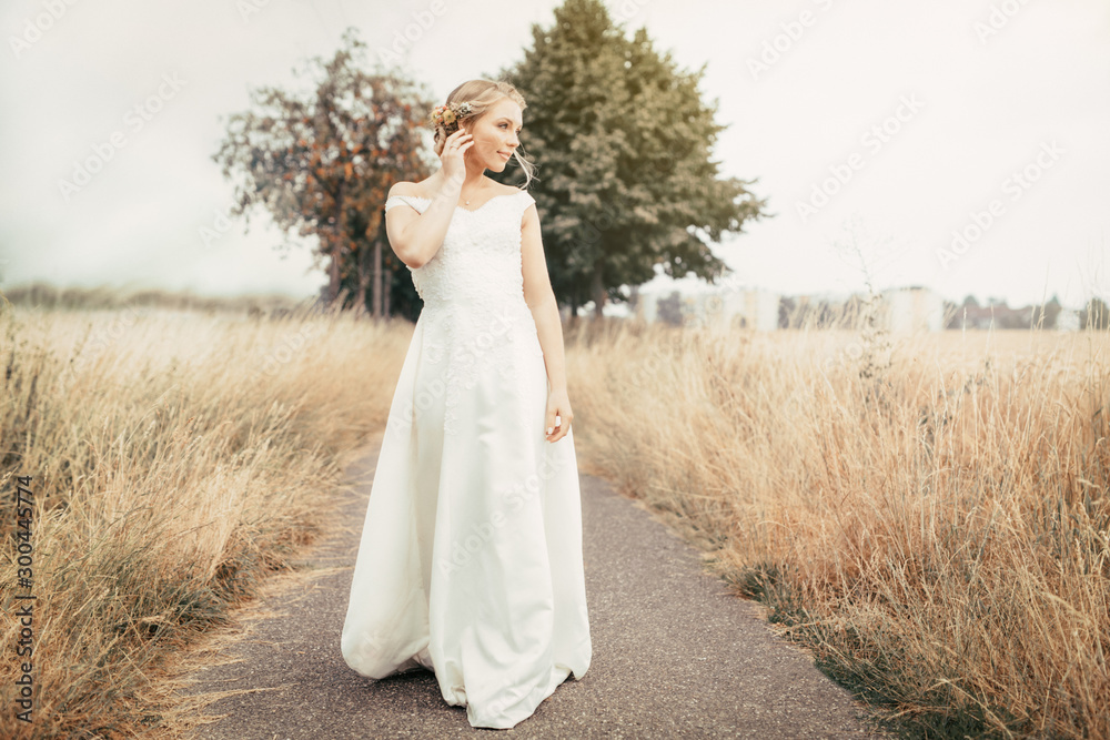 blonde wedding bride in white dress outside on field