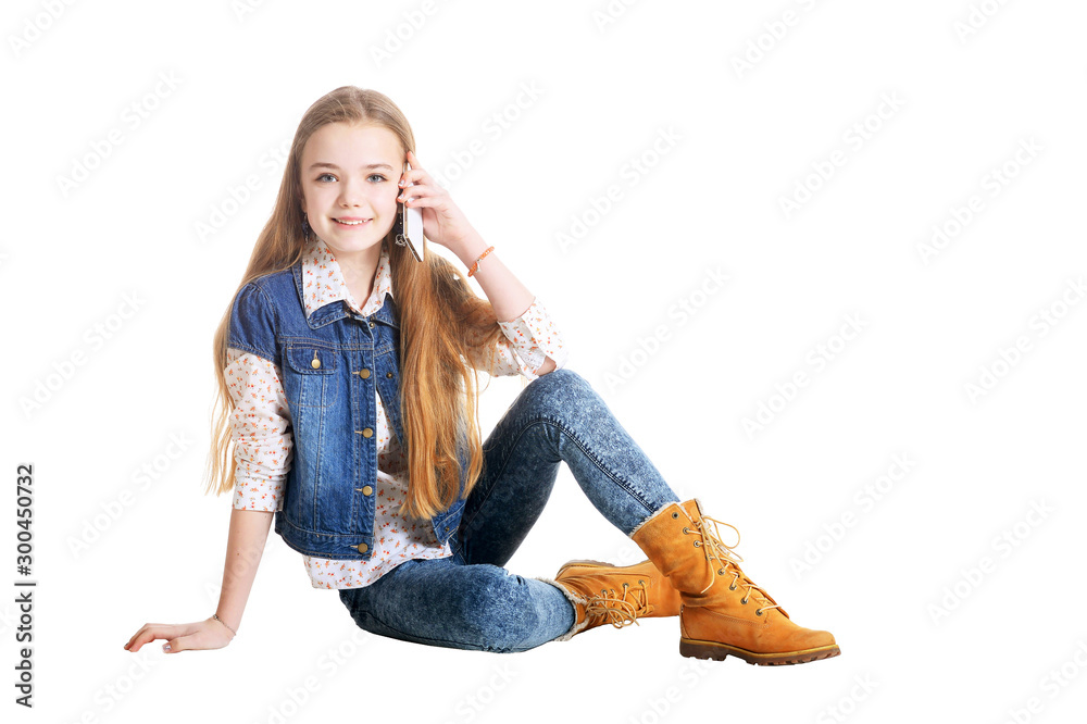 Happy little girl in jeans talking on phone