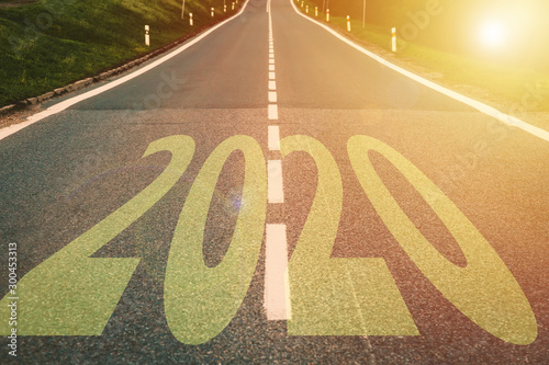 Concept of New Year 2020 Celebration. Word 2020 on highway road during golden sunset.