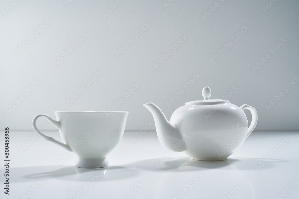 Composition with white porcelain tea-ware on a light gray background with a delicate bouquet of flowers