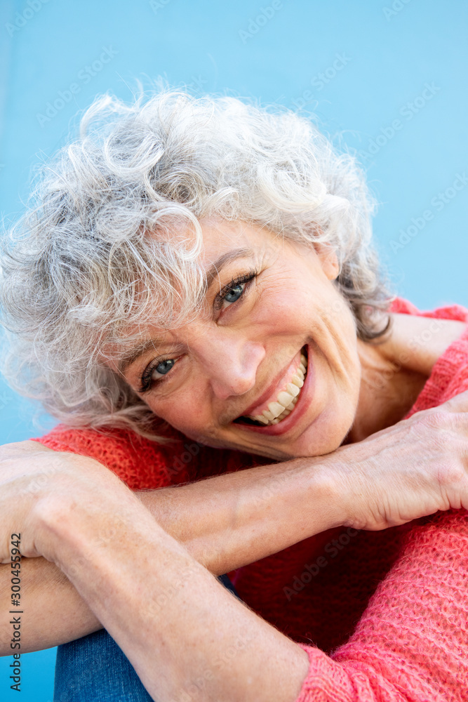 Close up beautiful older woman smiling by blue wall