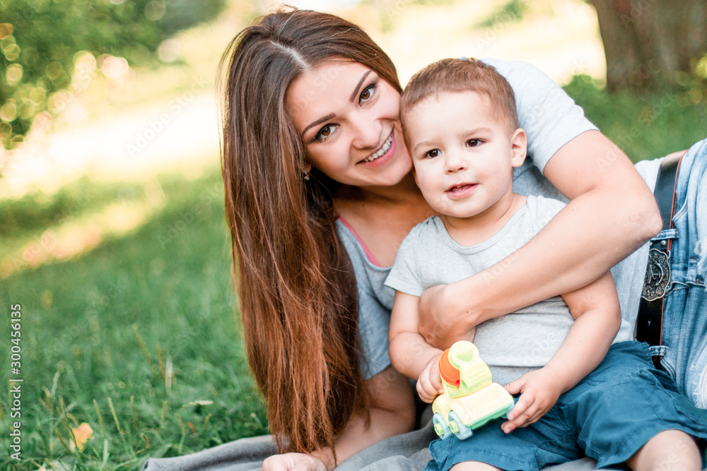 Mother with little son spend time together in green park. Mother with little son spend time together in green park.