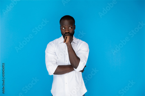 thoughtful afro-american in white shirt on blue background