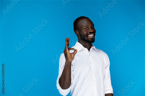 Smiling cute afroamerican guy shows the okay by his fingers