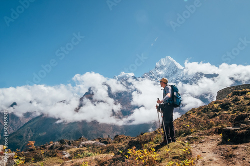 Fotografija Young hiker backpacker man using trekking poles enjoying the Thamserku 6608m mountain during high altitude Acclimatization walk