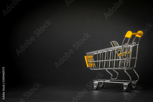 Empty shopping trolley on dark toned background with some copy space, financial crisis concept