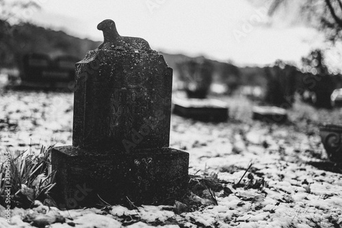 A child's tombstone with lamb statue in the snow