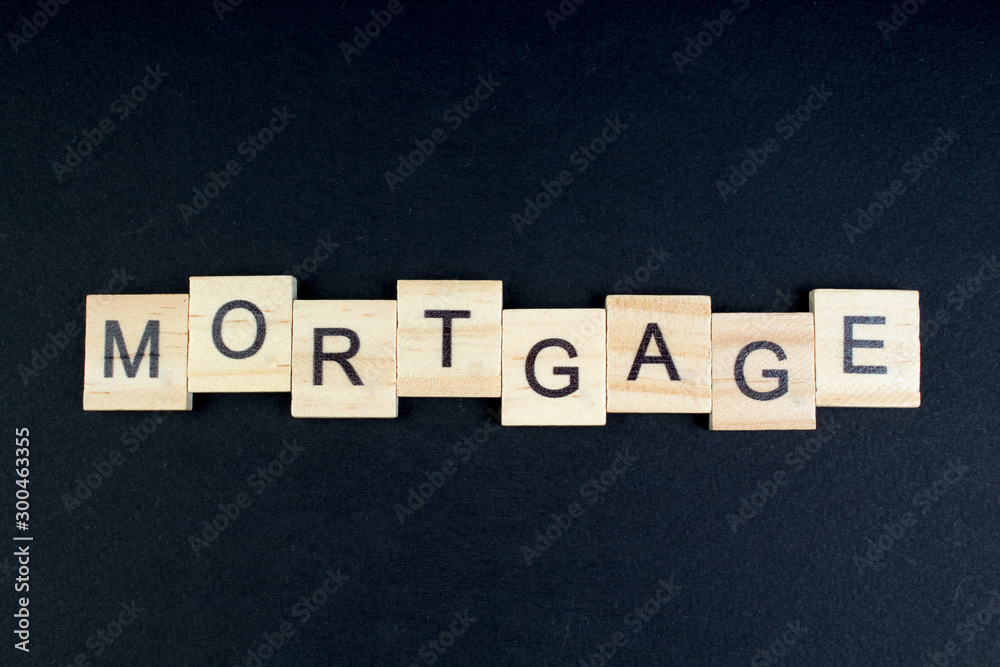 Obraz premium mortgage- word composed fromwooden blocks letters on black background, copy space for ad text.