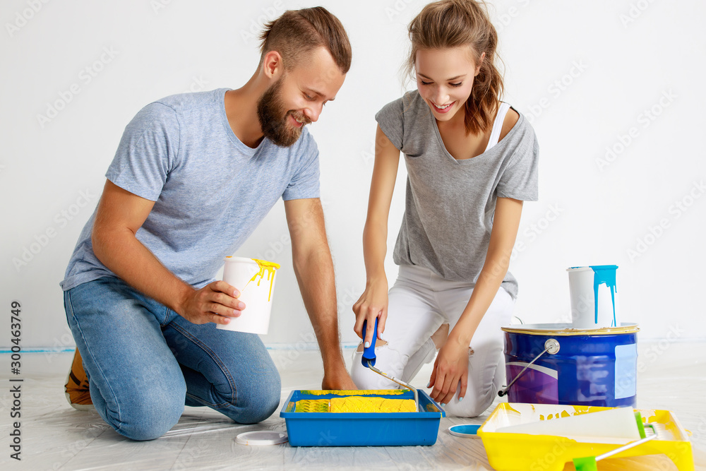 young happy couple is repairing and painting wall at home young happy couple is repairing and painting wall at home