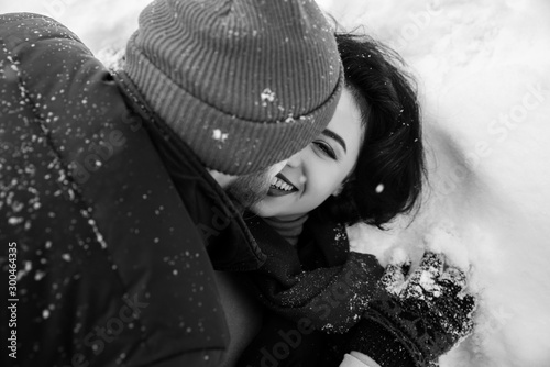 Black and white phoro of beautiful girl, she fooling around with her beloved boyfriend in the snow. Amazing girl with charming smile photo