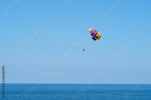 Skydiver on colorful parachute in blue sky. Active lifestyle, extreme sport, summer holidays, travel, vacation concept, copy space.