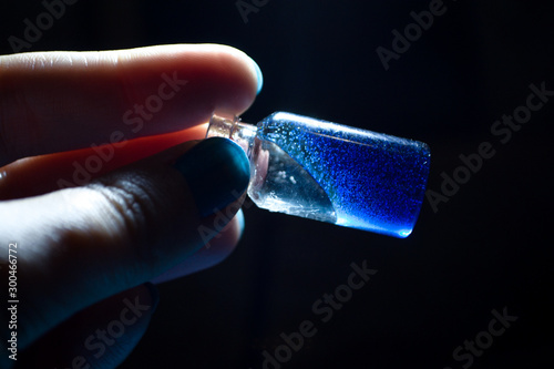hand holds bottle with blue magical glowing liquid