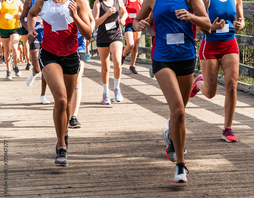 High school girls cross country runners crossing a wood bridge during a race