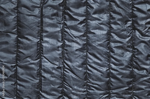 Shiny clothing background. Black background from quilted material.