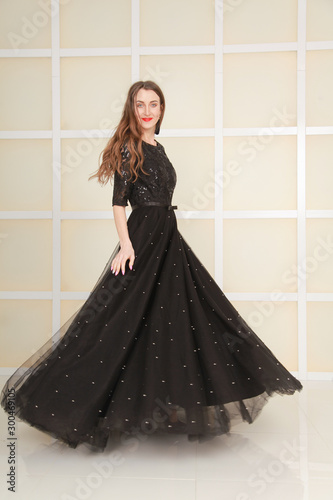 elegant slim adult woman in fashion long evening lace black dress on white studio background, full length body