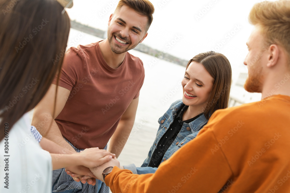 Group of happy people holding hands together, outdoors Group of happy people holding hands together, outdoors