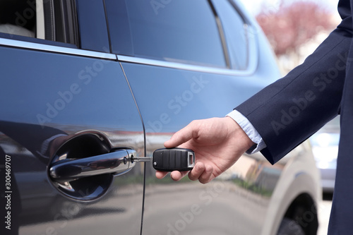 Businessman opening car door with key, closeup