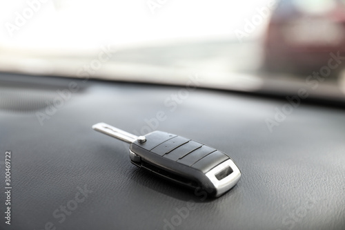 Car key on dashboard in auto against blurred background