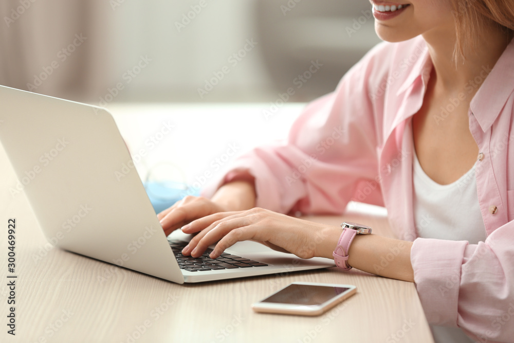 Young woman using laptop at table indoors, closeup Young woman using laptop at table indoors, closeup