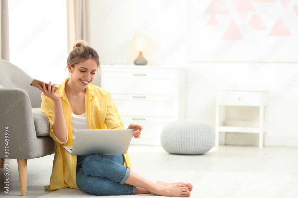 Young woman with smartphone using laptop at home Young woman with smartphone using laptop at home