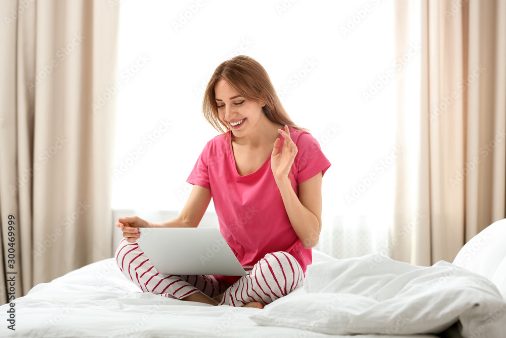 Young woman using modern laptop in bedroom Young woman using modern laptop in bedroom