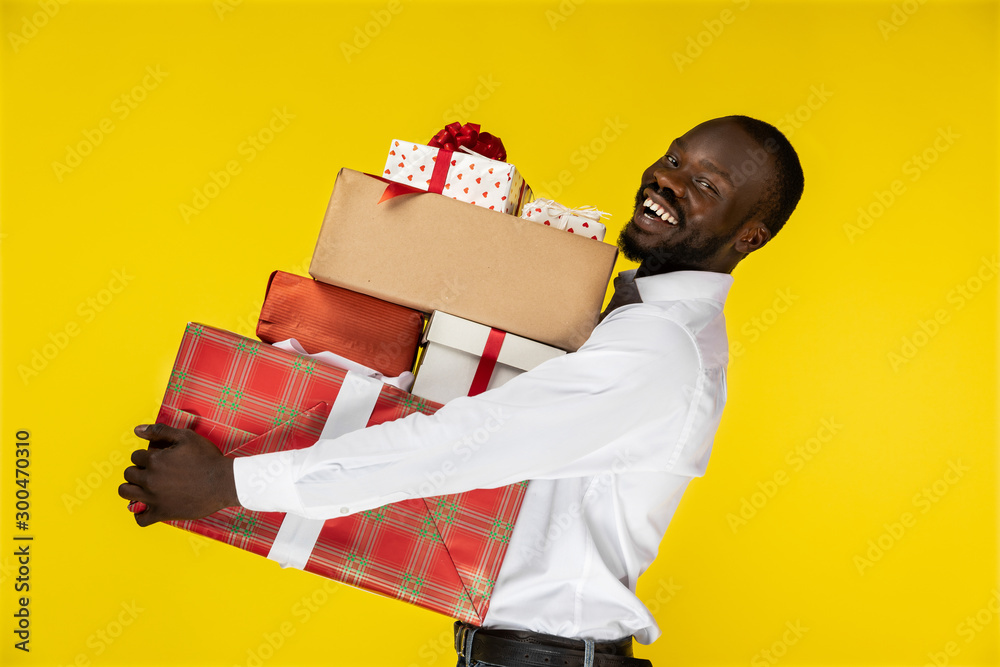 Ταπετσαρία laughing bearded young afroamerican guy with lots of presents on the yellow back