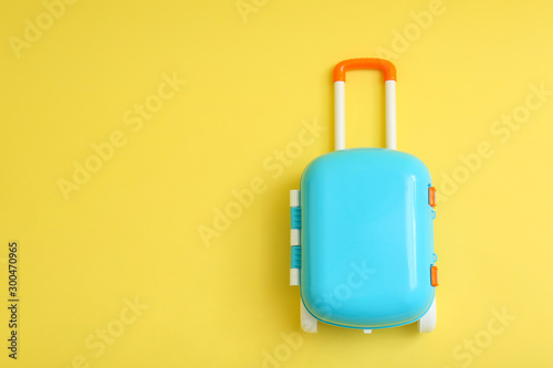 Stylish blue little suitcase on yellow background, top view. Space for text
