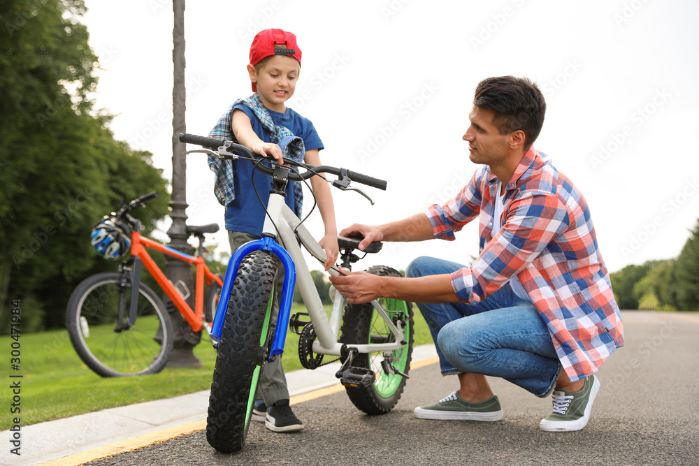 Dad teaching son to ride bicycle outdoors Dad teaching son to ride bicycle outdoors