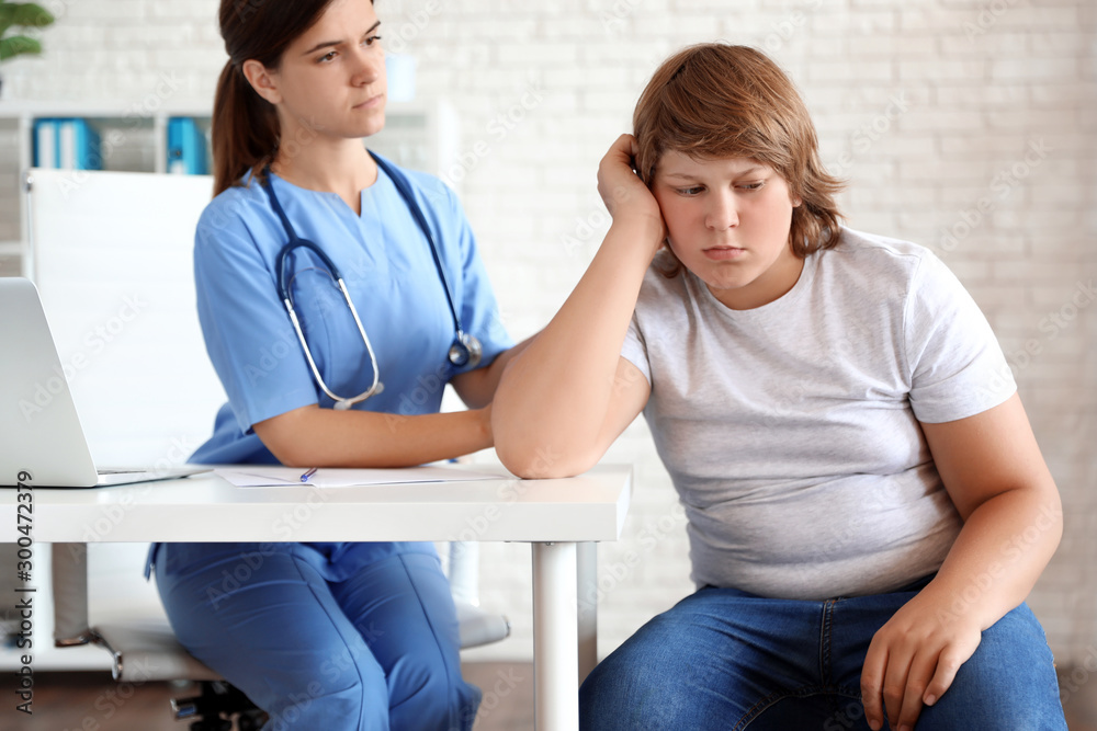 Emotional overweight boy consulting with doctor in clinic