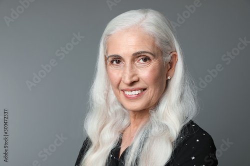 Portrait of beautiful mature woman on grey background, space for text