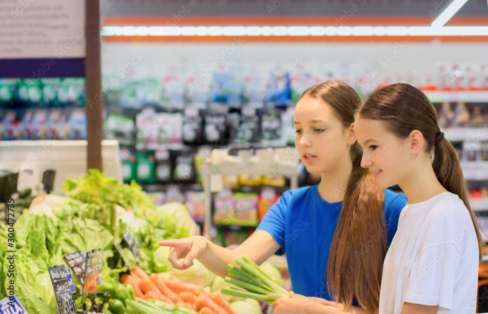 Teen girls shopping in supermarket reading product information. Choosing daily product.Concept of healthy food, bio, vegetarian, diet.