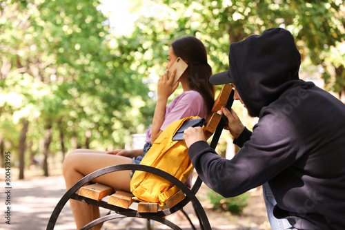 Φωτογραφία Thief stealing wallet from backpack of careless woman talking on mobile phone in