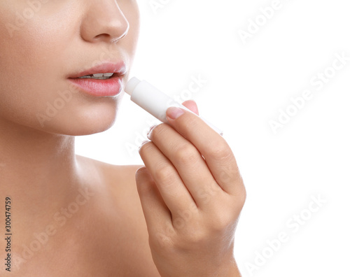 Young woman with cold sore applying lip balm against white background  closeup