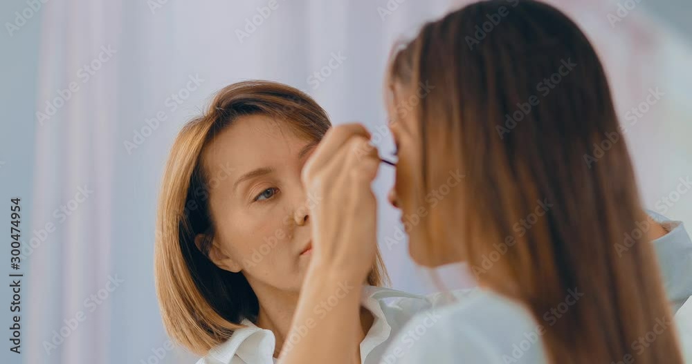 Master of the beauty salon applies mascara to the eyelashes. Makeup artist working on a model, doing eye makeup. Portrait view. Master of the beauty salon applies mascara to the eyelashes. Makeup artist working on a model, doing eye makeup. Portrait view.