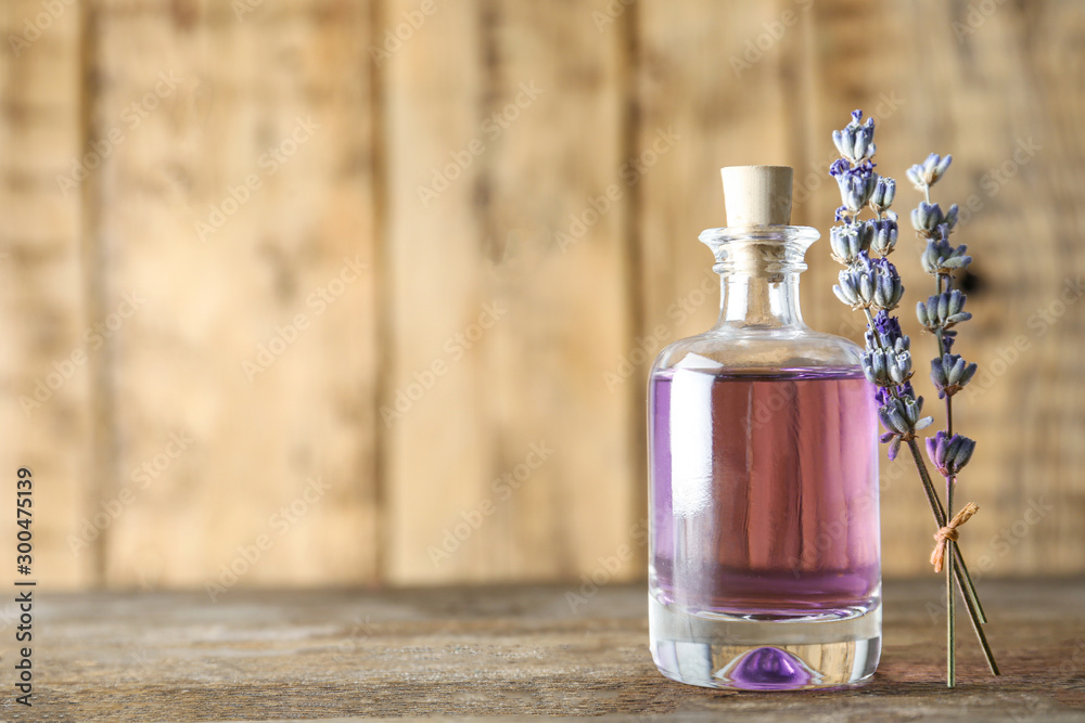 Bottle of natural essential oil and lavender flowers on wooden background. Space for text Bottle of natural essential oil and lavender flowers on wooden background. Space for text