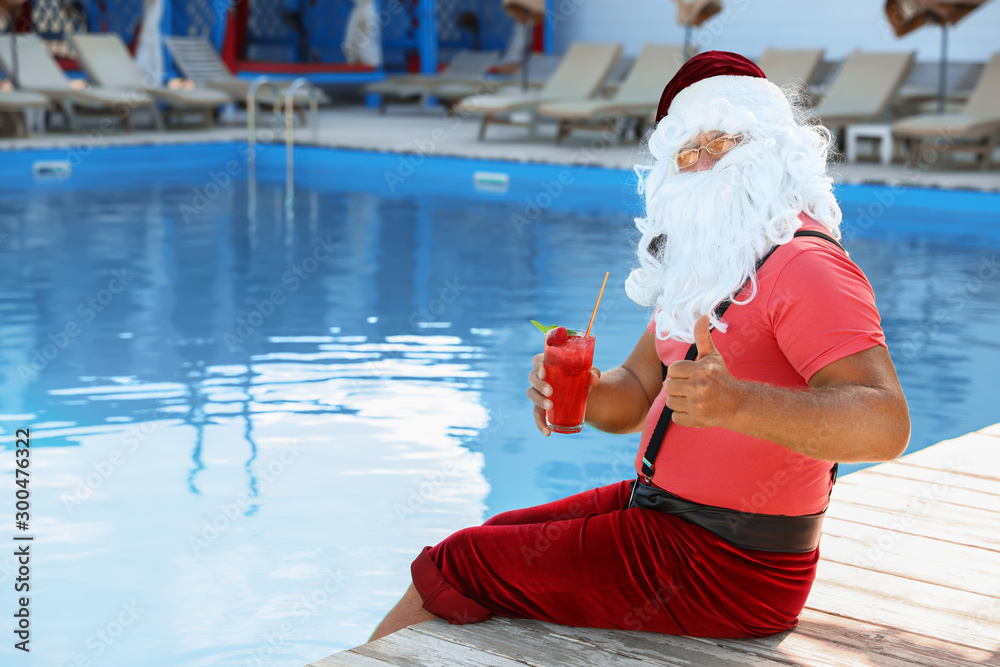 Obraz premium Authentic Santa Claus with cocktail near pool at resort