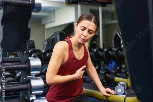 Young woman having heart attack in gym