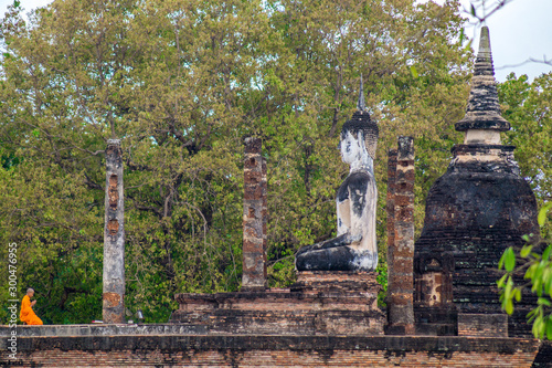 munk praying at a buddha statue in jungle photo