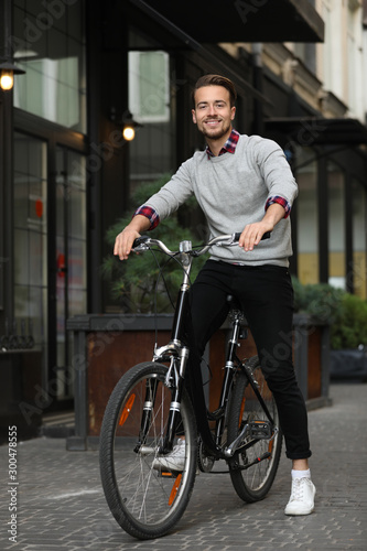 Handsome happy man riding bicycle on city street