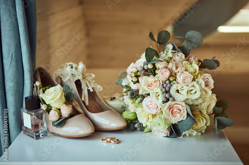 bridal accessories such as shoes, bouquet , ring and perfume lie on a table