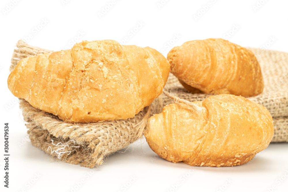 Group of three whole fresh baked mini croissant with jute bag isolated on white background