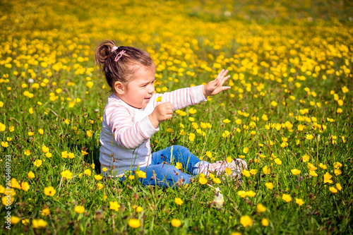 Young girl sitting on meadow, reaching out hand, blurred background