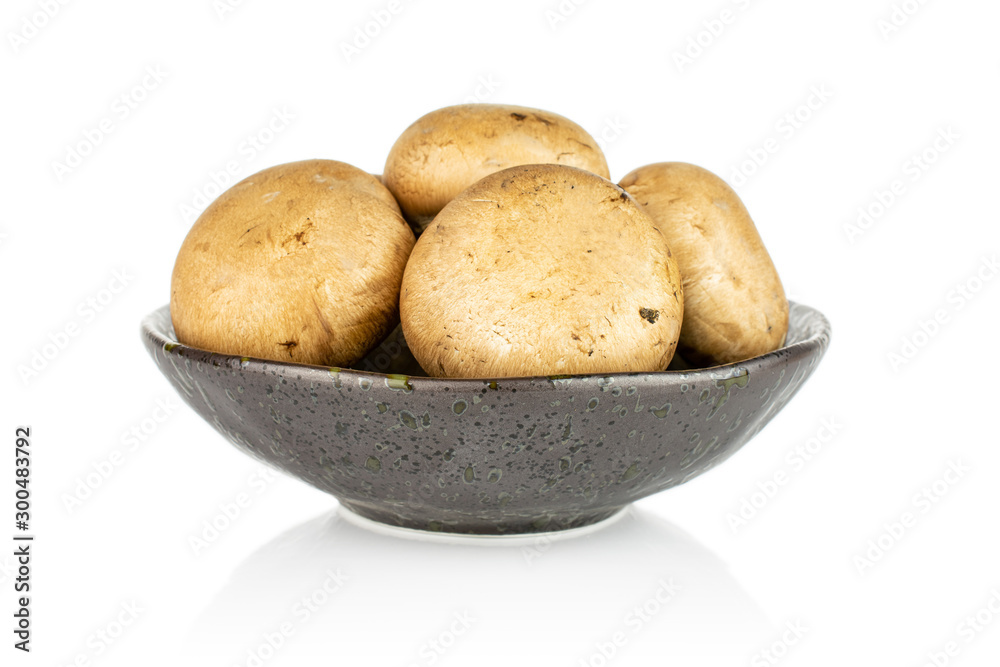 Group of four whole fresh brown champignon in dark ceramic bowl isolated on white background Group of four whole fresh brown champignon in dark ceramic bowl isolated on white background