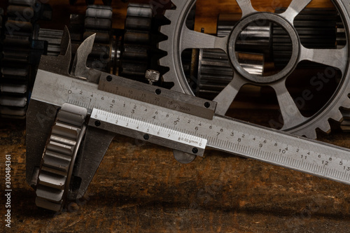 vernier callipers, micrometer and bore gauge on a workbench with gears in the background