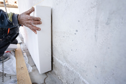 Murais de parede Worker placing styrofoam sheet insulation to the wall at construction site Rigid