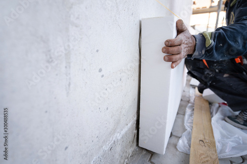 Tela Worker placing styrofoam sheet insulation to the wall at construction site Rigid