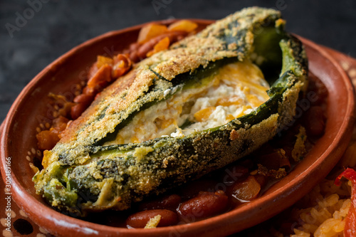 Chille relleno and Mexican rice served in traditional clay plates