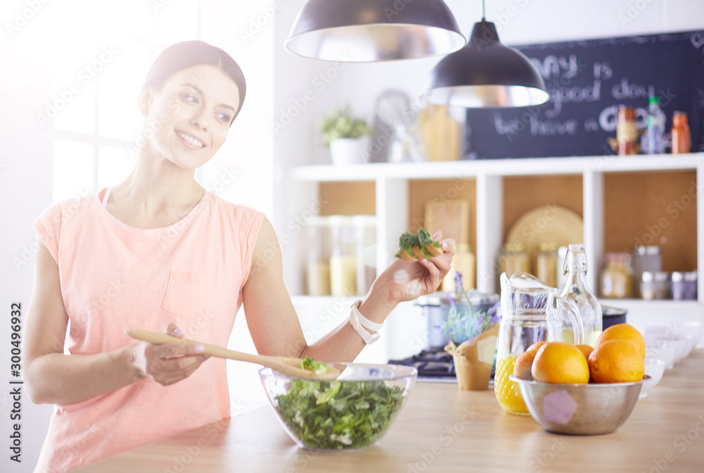 Smiling young woman mixing fresh salad in the kitchen. Smiling young woman mixing fresh salad in the kitchen.